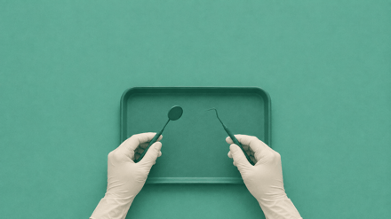 Top-down view of gloved hands holding a dental mirror and probe over a teal instrument tray.